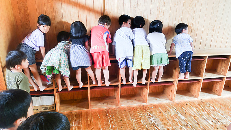 木製ロッカーの前で帰りの準備をするあゆみの森こども園の子どもたち