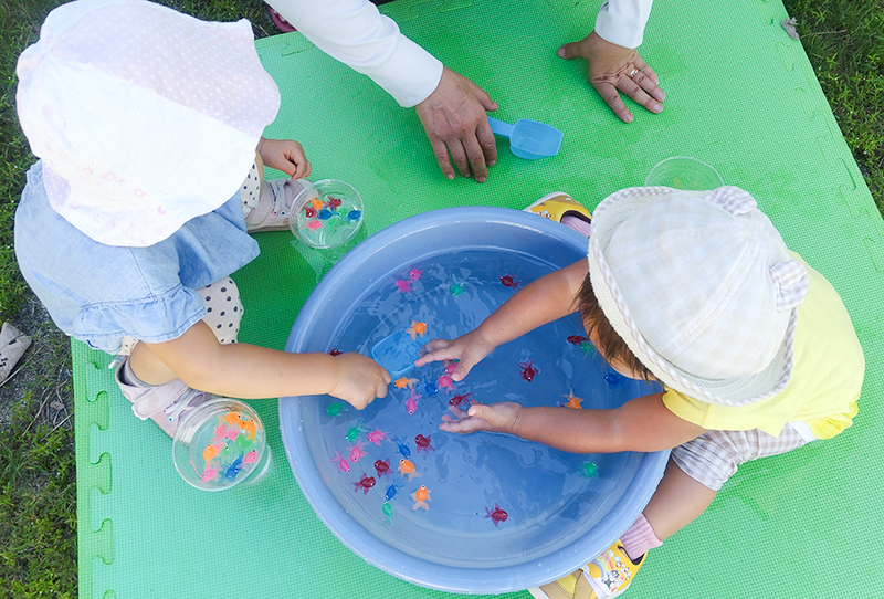 緑色のボールプールで全身を使って遊ぶこども園の園児たち