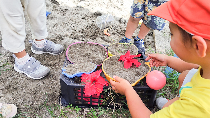 ピンクの帽子をかぶって砂遊びを楽しむあゆみの森こども園の子ども