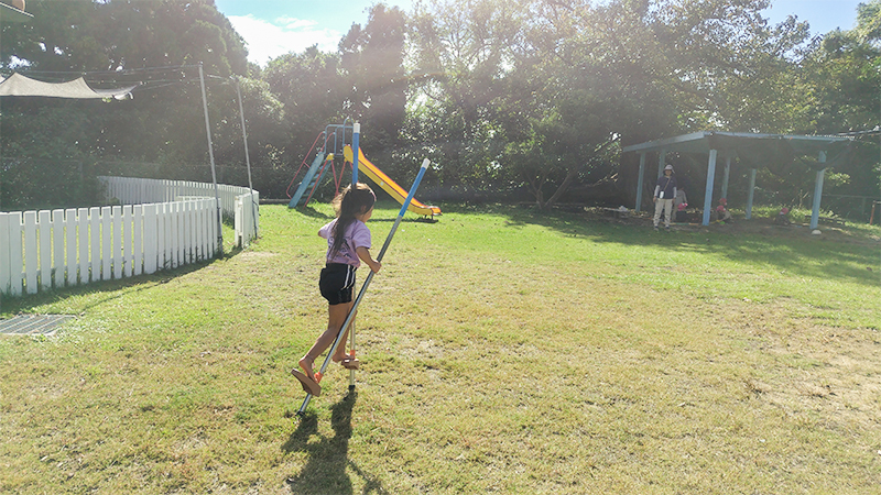 屋久島の自然に囲まれた園庭で縄跳び遊びをする子どもたち
