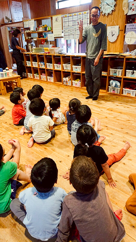保育室内で熱田園長による読み聞かせを楽しむ子どもたち