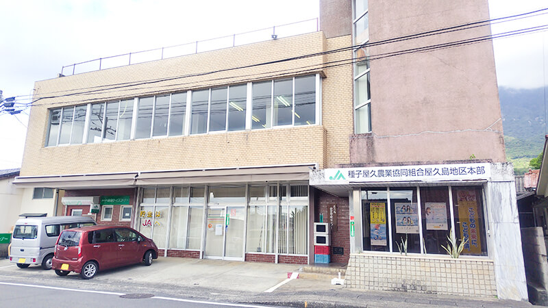 屋久島の山々を背景にした種子屋久農協の建物外観