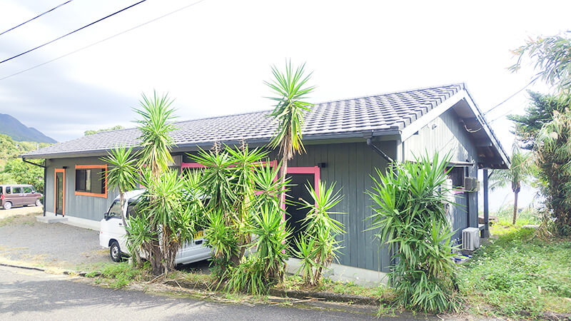 亜熱帯植物に囲まれた黒い外壁のあゆみの森こども園職員寮の外観